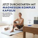Frau sitzt auf einer Yogamatte. Auf einem Tisch steht eine Flasche Magnesium Komplex Kapseln.