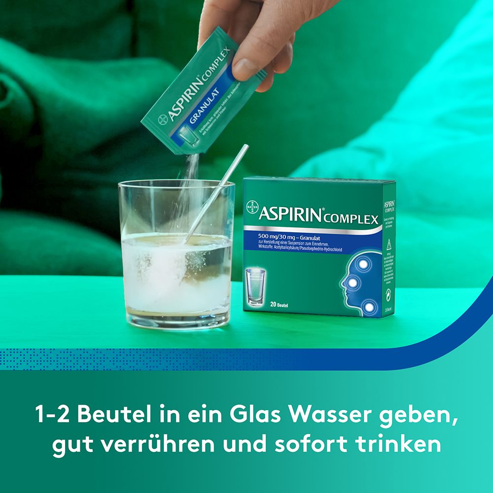 Hand gießt Pulver aus einem Beutel in ein Glas Wasser. Text: 1-2 Beutel in ein Glas Wasser geben, gut verrühren und sofort trinken.