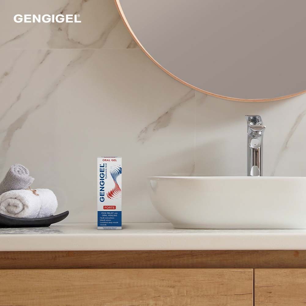 Badezimmer-Szene. Gengigel® Gel forte-Verpackung steht auf einer Ablage. Spiegel und Waschbecken im Hintergrund.