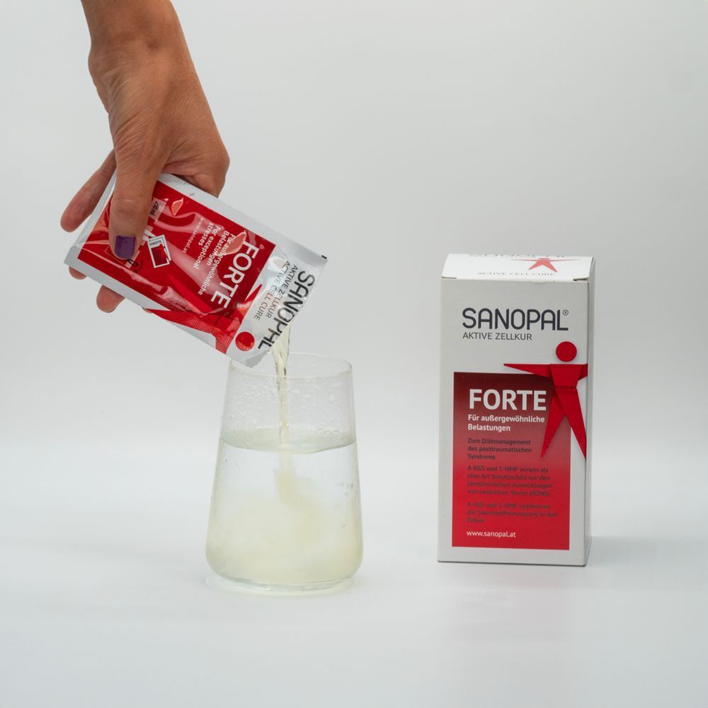 Person gießt Pulver aus einem Beutel in ein Glas Wasser. Sanopal Forte-Verpackung im Hintergrund.