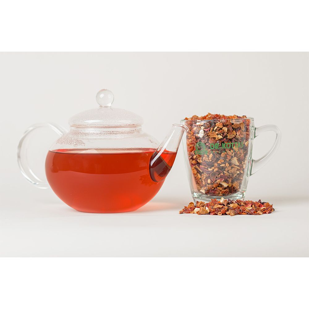 Glaskanne mit rotem Getränk, daneben eine Tasse mit Früchtetee. Tee lose daneben.