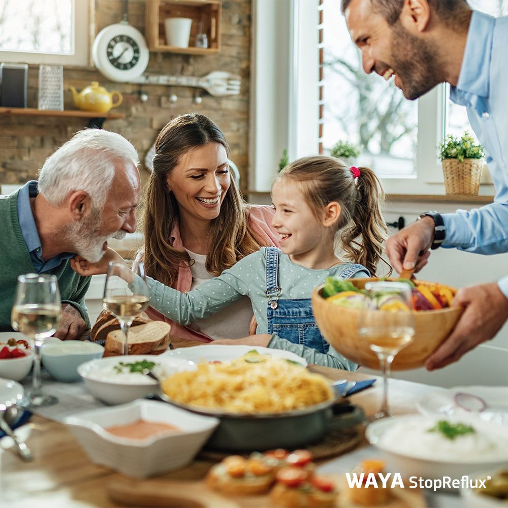 Familie am Tisch. WAYA StopReflux®-Packung im Hintergrund. Essen und Getränke.