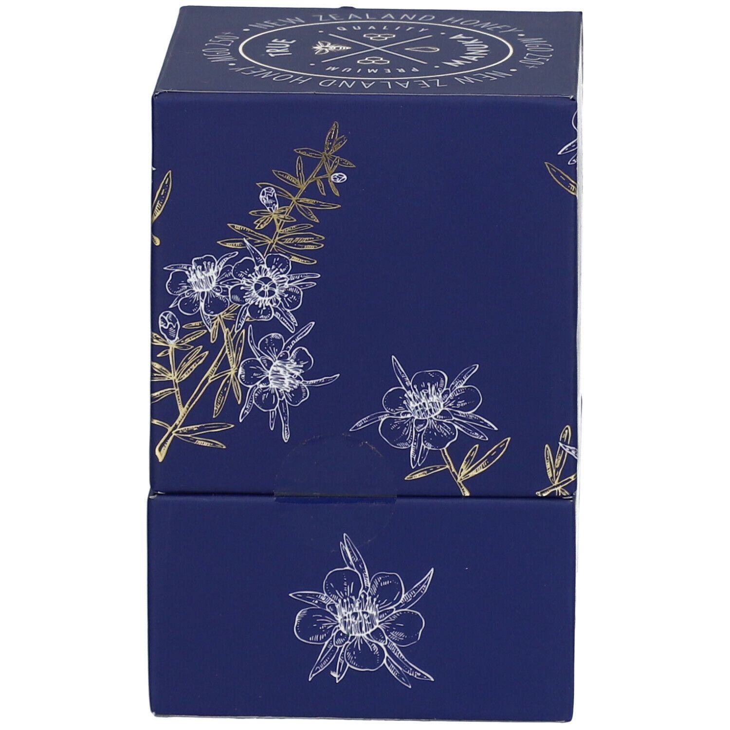 Dunkelblaue Schachtel mit weiß-goldenen floralen Motiven. Seitenansicht. Keine Produktbezeichnung sichtbar.