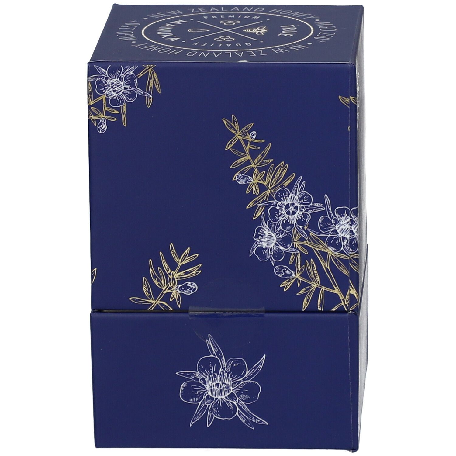 Dunkelblaue Schachtel mit weiß-goldenen floralen Motiven. Seitenansicht. Keine Produktbezeichnung sichtbar.