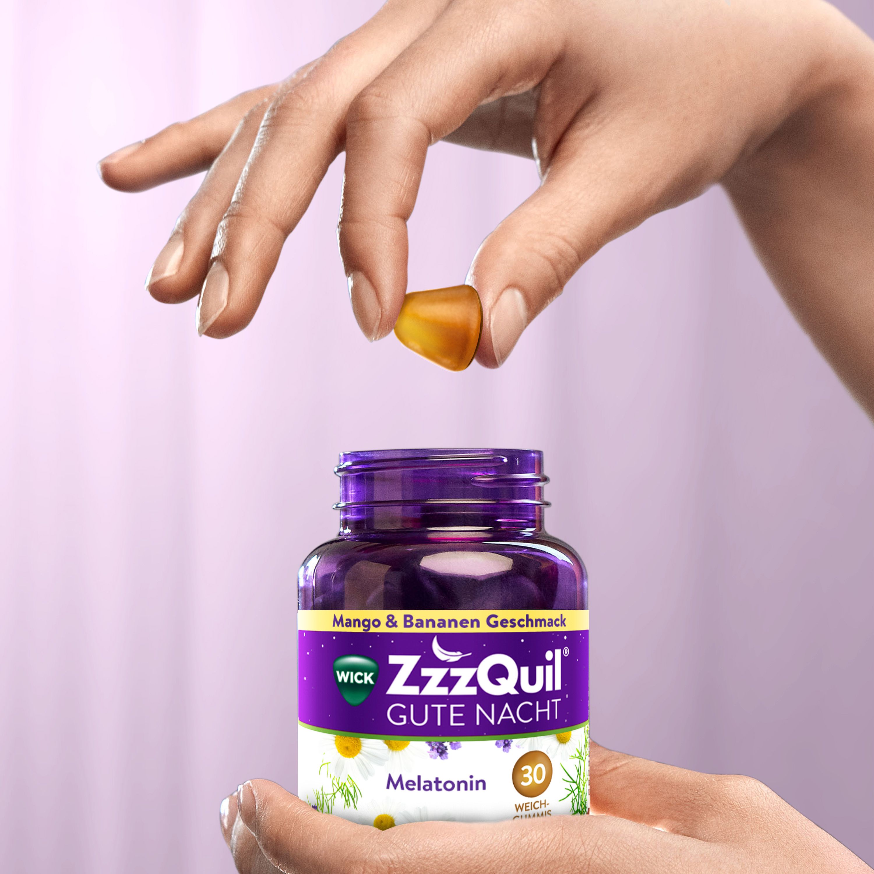 Hand hält Weichgummi vor Flasche WICK ZzzQuil Gute Nacht.
