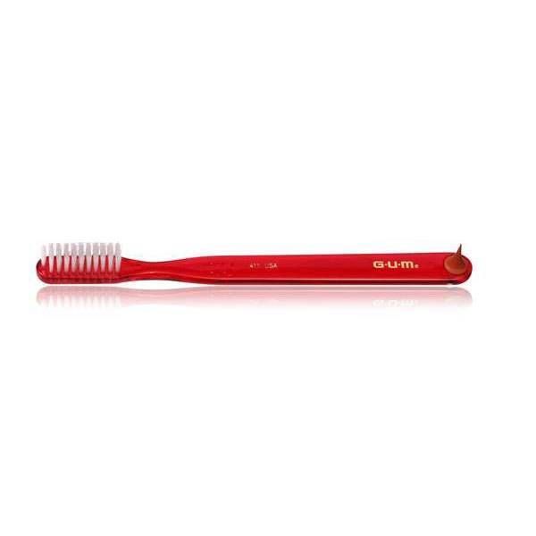 Brosse à dents rouge avec poils blancs. Inscription G.U.M. sur le manche.