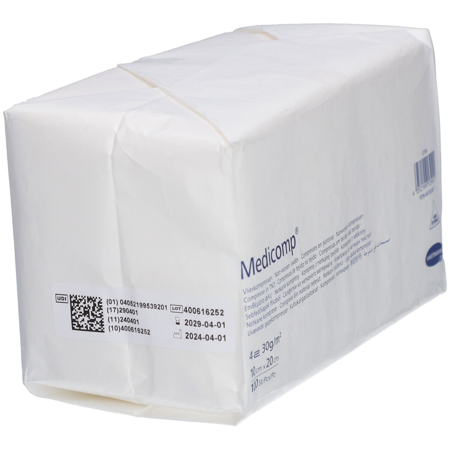 Paquet blanc rectangulaire avec "Medicomp". Contient des compresses. Dimensions: 10x20cm. 4 couches. Code-barres, numéro de lot et date d'expiration.
