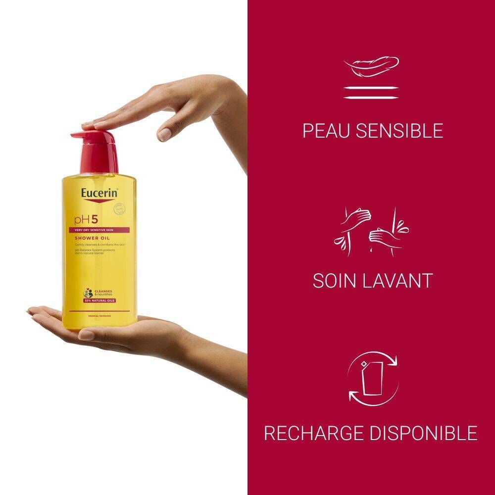 Main tenant un flacon d'huile de douche Eucerin pH5. Texte : Peau sensible, soin lavant, recharge disponible.