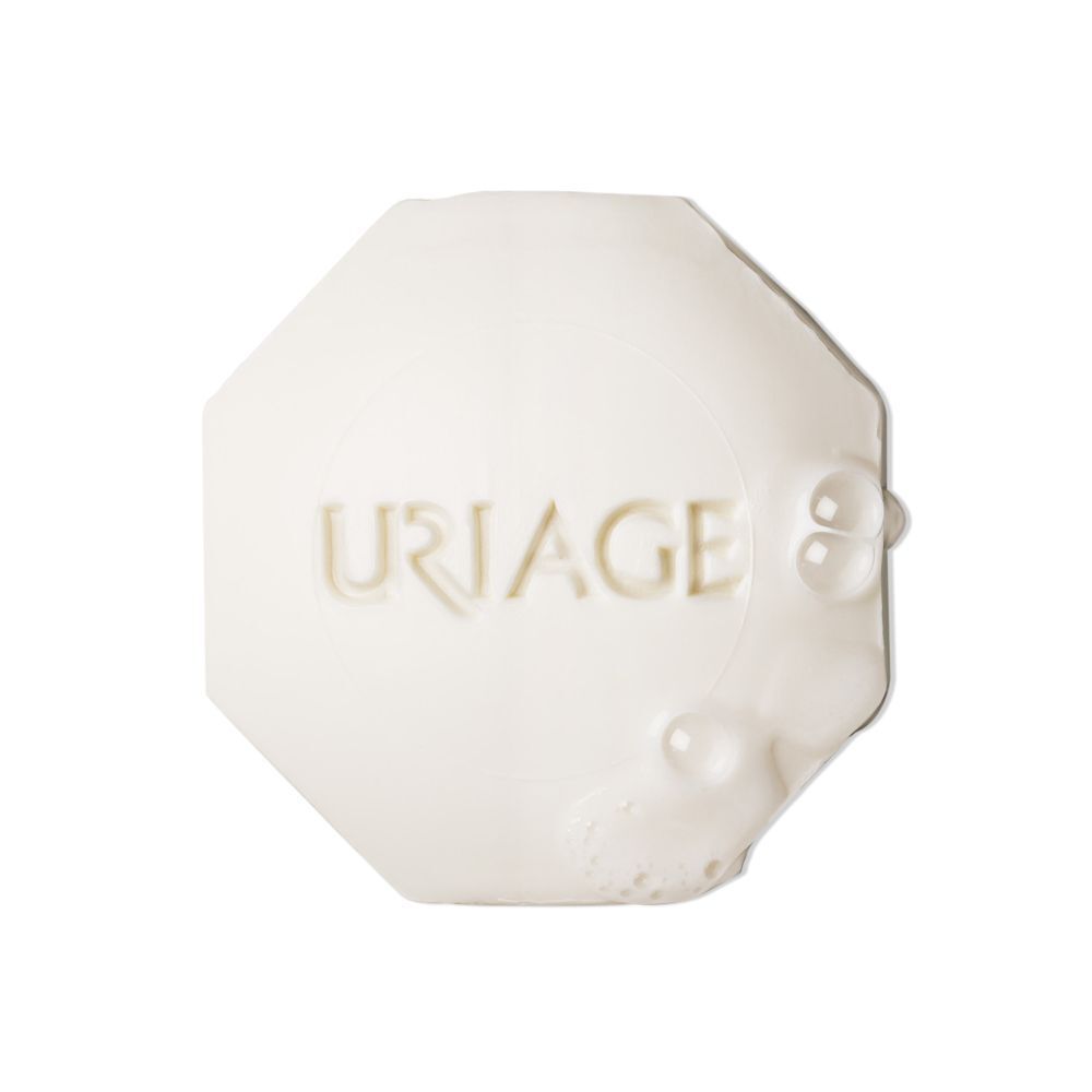 Wit, achthoekig stuk zeep. Uriage-logo in reliëf. Enkele zeepbellen.