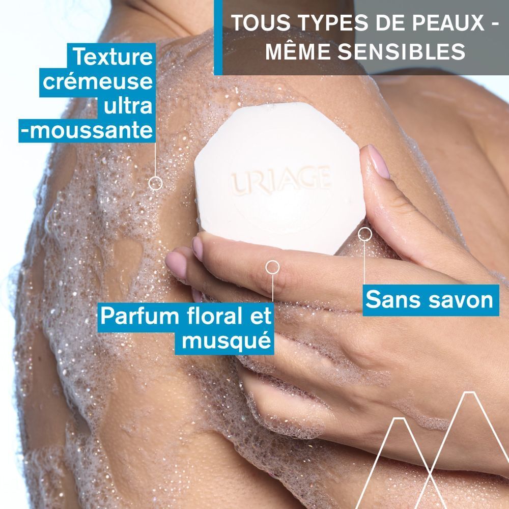 Personne utilisant du savon. Savon octogonal avec logo Uriage. Texte : texture crémeuse, parfum floral, sans savon.