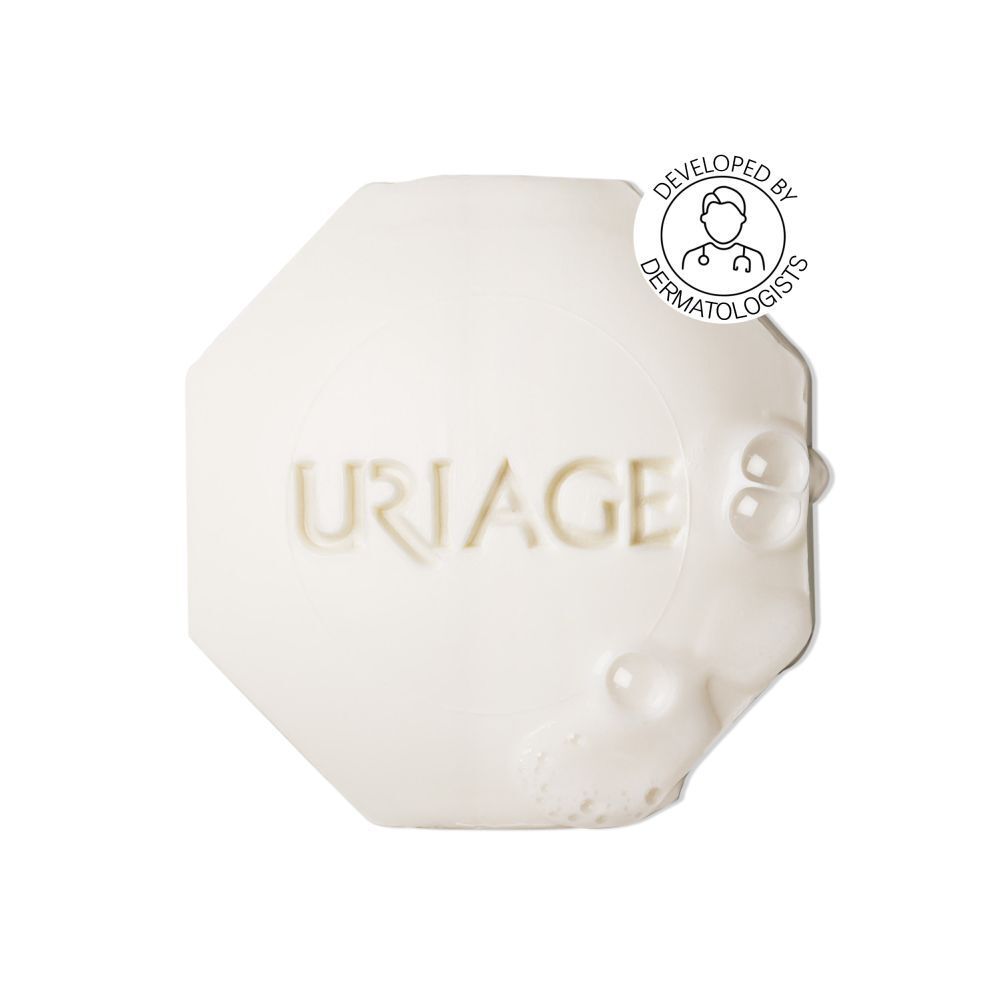 Wit, achthoekig stuk zeep. Uriage-logo in reliëf. Met het logo 'Developed by Dermatologists'.