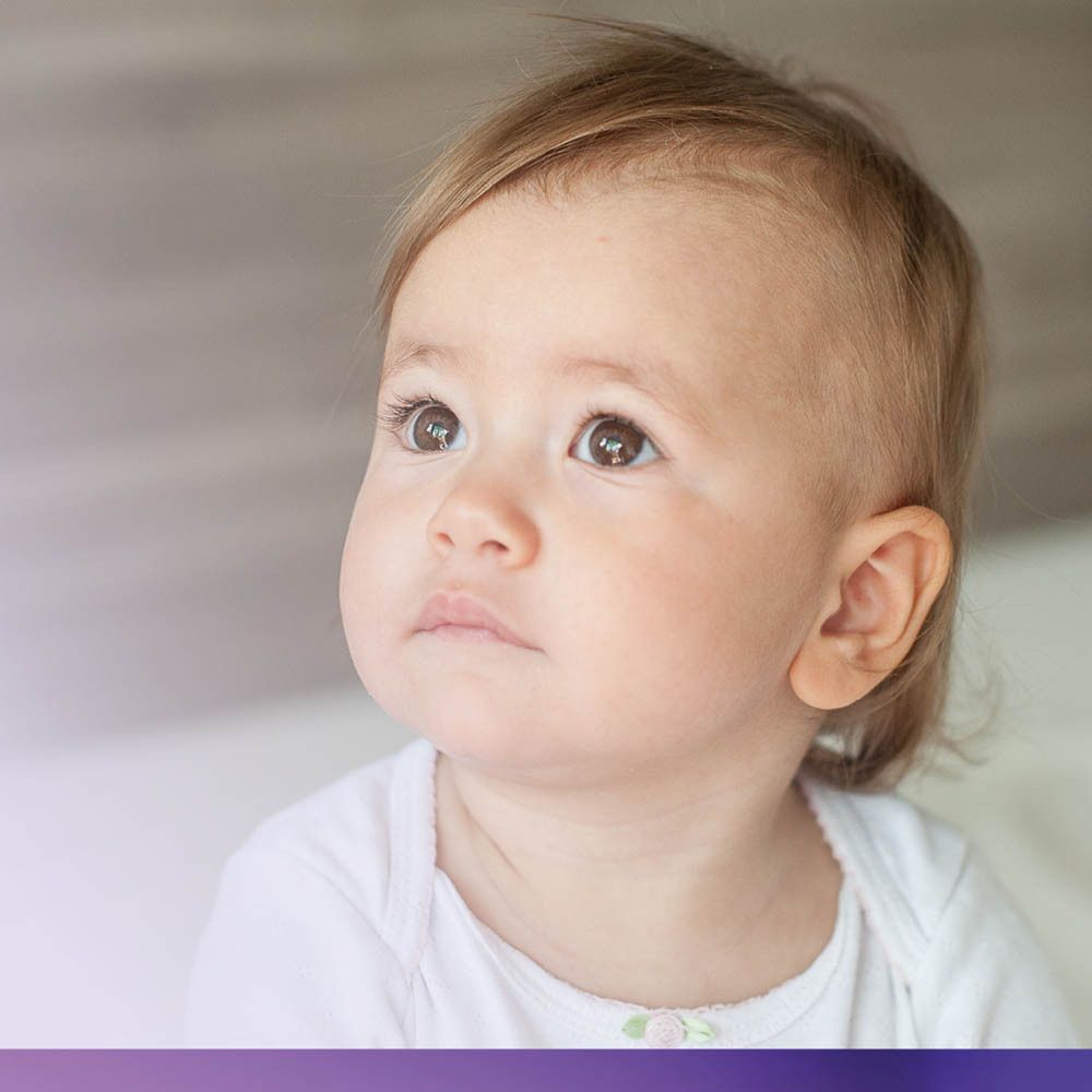Babygezicht, omhoog kijkend. Lichte omgeving. Focus op het gezicht van de baby.