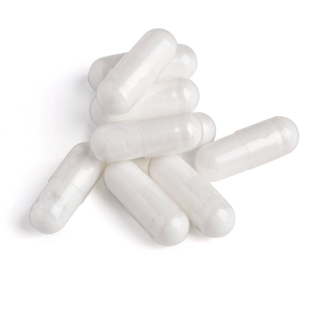 Tas de gélules blanches. Les gélules sont oblongues, lisses et translucides.