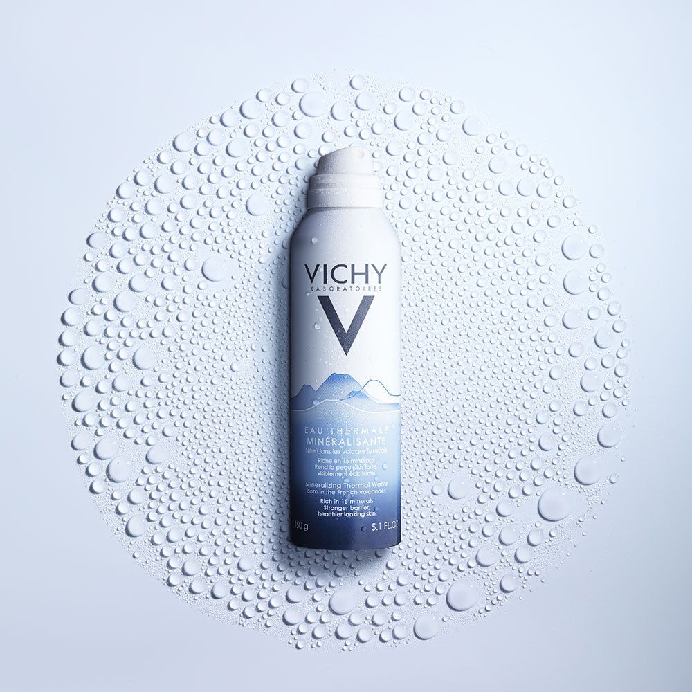 Sprayfles omringd door waterdruppels. Productnaam en logo duidelijk zichtbaar.