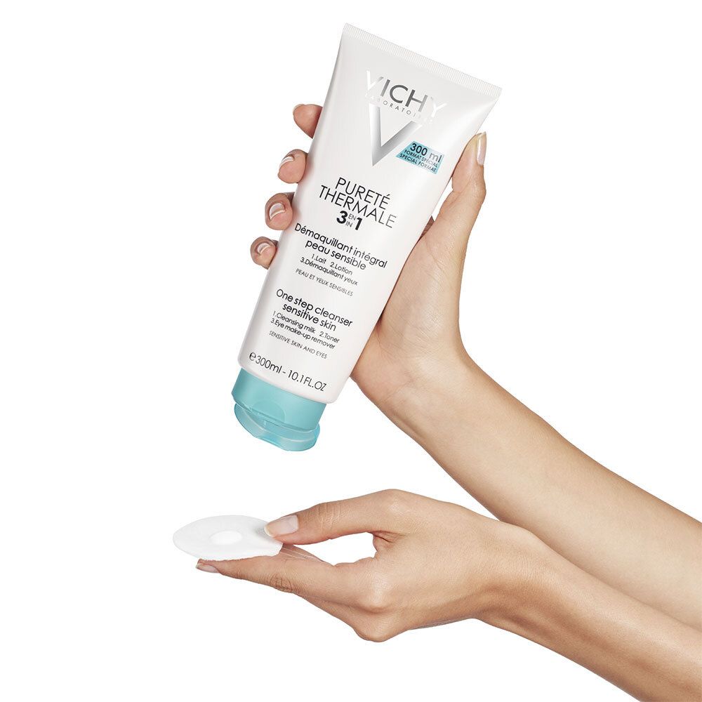 Mains tenant un tube VICHY Pureté Thermale 3 en 1 et un coton. Produit et accessoires.