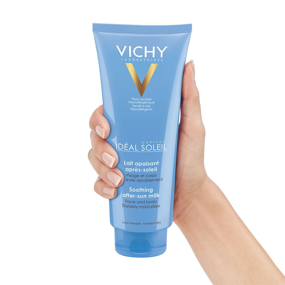 Main tenant un tube bleu VICHY CAPITAL SOLEIL. Lait après-soleil visage et corps. Hypoallergénique.