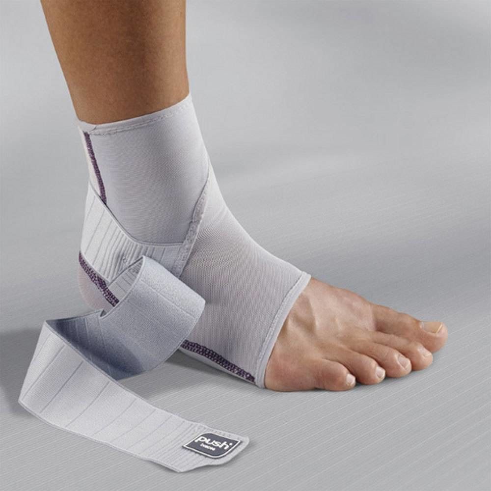 Attelle de cheville grise sur pied. Fermeture velcro et logo Push. Attelle avec bande de fixation.
