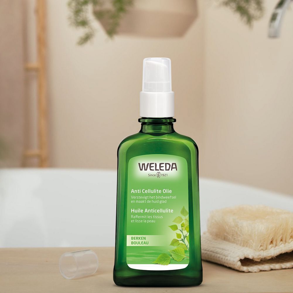 Flacon vert avec vaporisateur. Étiquette avec nom du produit. Marque Weleda. À côté : éponge et bouchon.