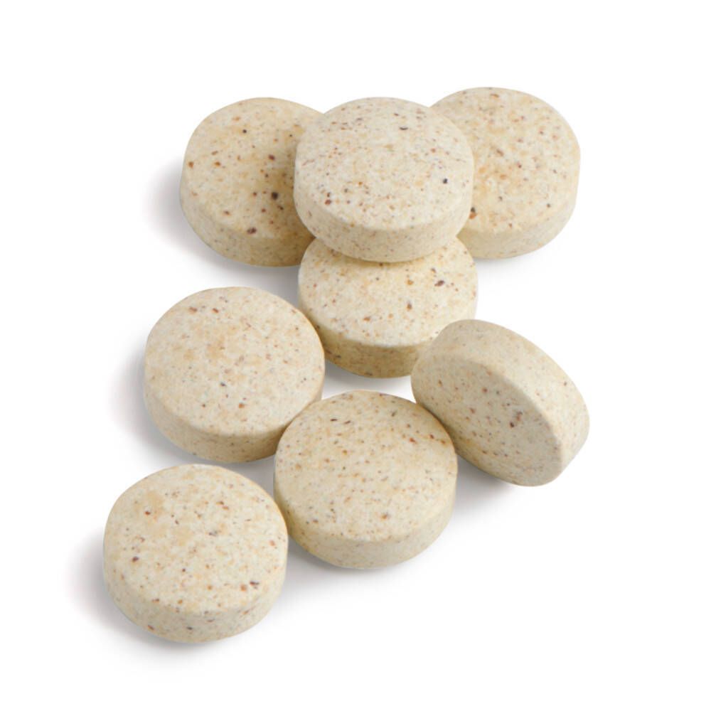 Zeven ronde, beige tabletten. Oppervlak met kleine puntjes. Op witte achtergrond.
