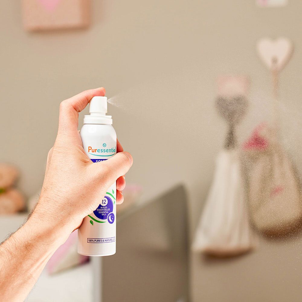 Persoon houdt witte sprayfles met paarse kop vast. Sproeimist zichtbaar.