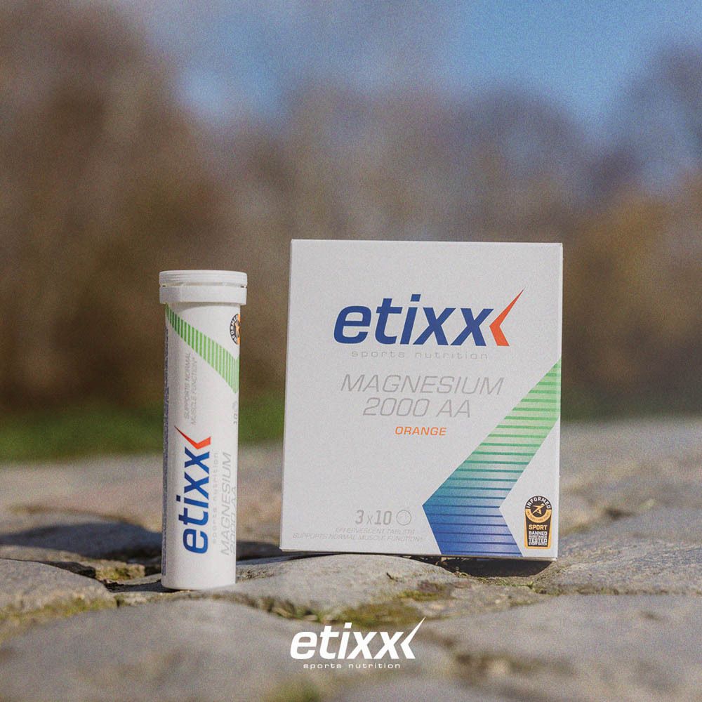 Etixx Magnesium 2000 AA bruistabletten. Verpakking en tube op stenen grond. Oranje tekst. Groen-wit design.