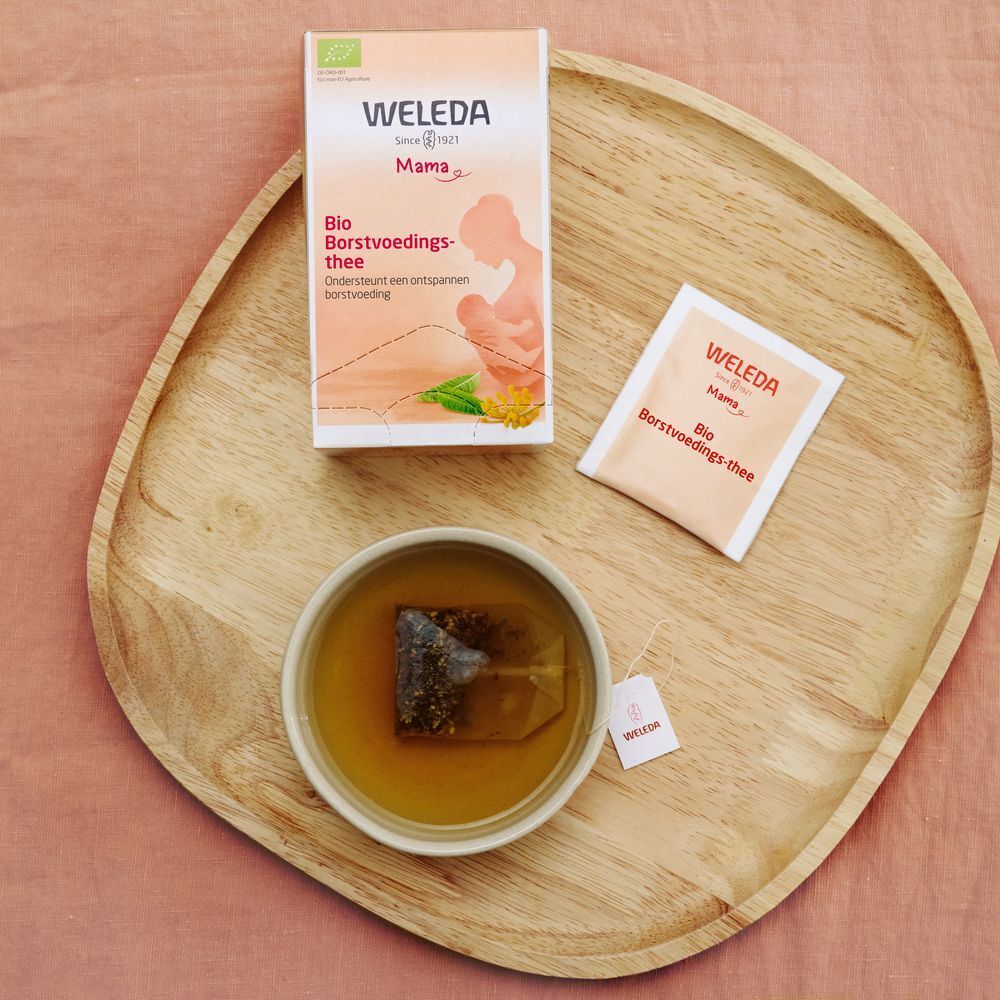 Weleda Mama Stilltee-Packung und Teebeutel auf Holztablett. Tasse Tee mit Teebeutel.