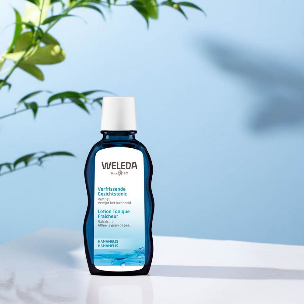Dunkelblaue Flasche mit weißem Deckel. Aufschrift: WELEDA, Lotion Tonique Fraîcheur. Hintergrund: hellblauer Farbverlauf.