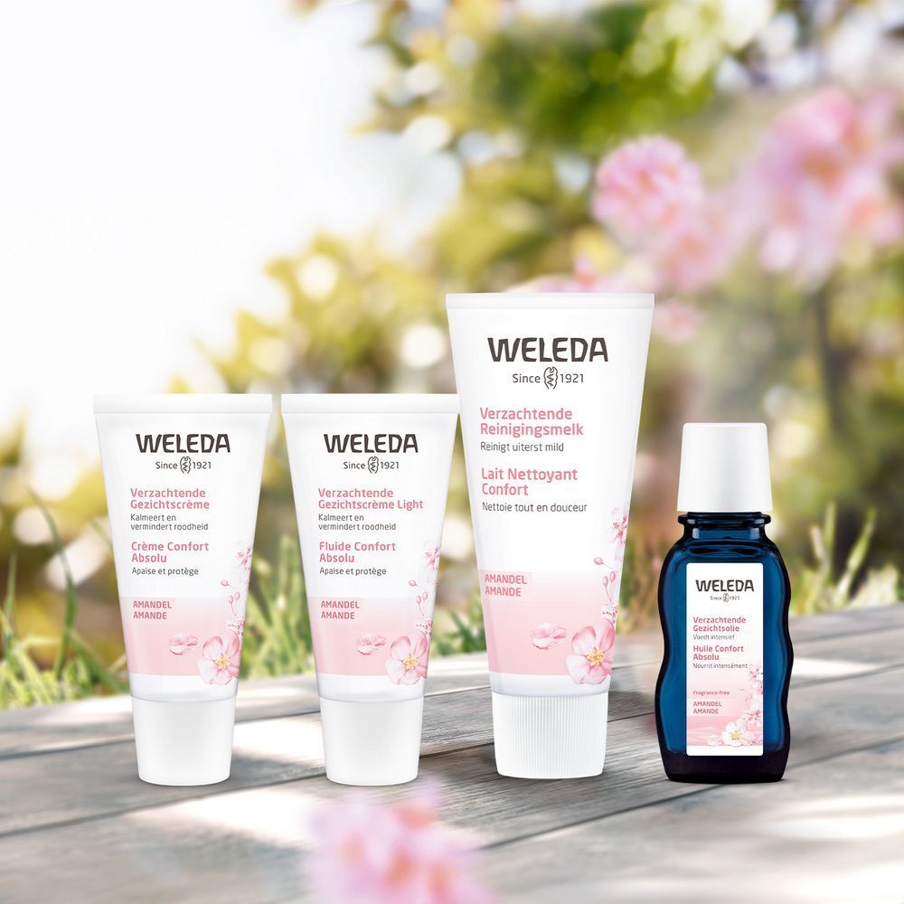 Gamme de produits Weleda sur bois. Tubes et flacon. Design rose et blanc. Texte : 'Verzachtende Reinigingsmelk', 'Lait Nettoyant Confort'. Illustrations florales.