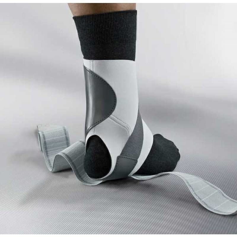 Orthèse de cheville grise et blanche, portée sur une jambe. Avec fermetures velcro. Bande grise. Chaussette noire.