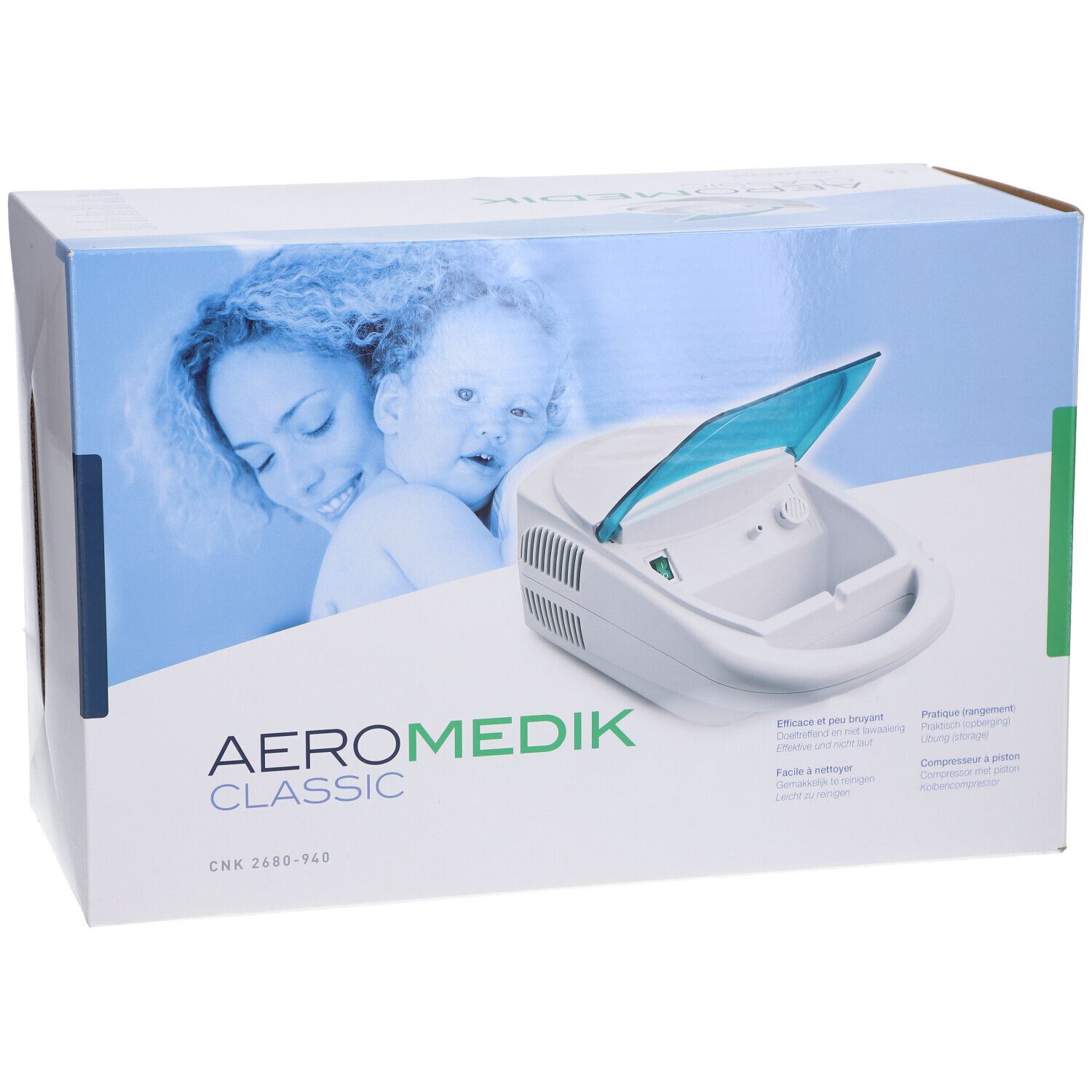 Aérosol Medik Classic dans son emballage. Appareil blanc avec couvercle bleu. Inscription: AERO MEDIK CLASSIC. Textes multilingues.