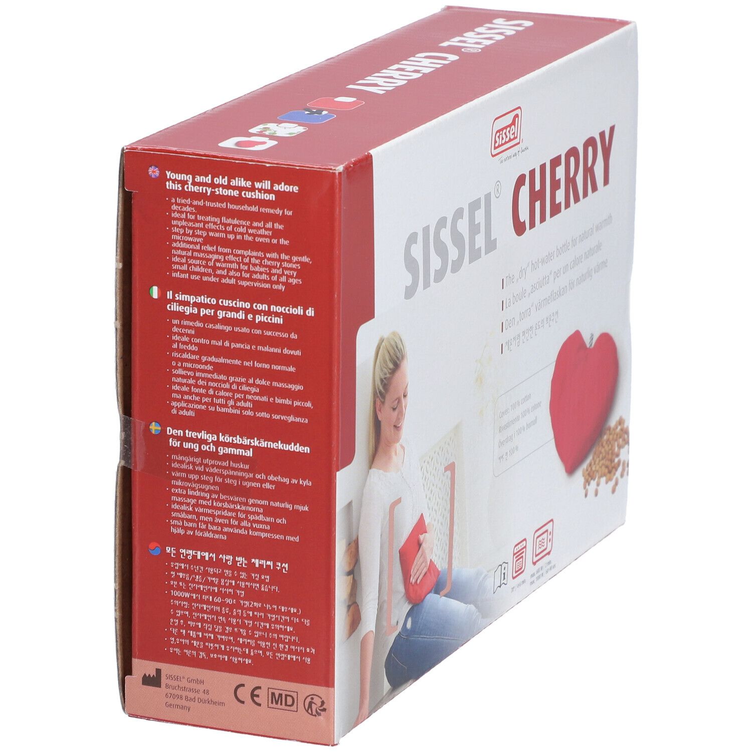 Verpackung Sissel Cherry. Rotes Herz-Kissen und Kirschkerne. Frau mit rotem Kissen. Text in mehreren Sprachen. Perspektivische Ansicht.