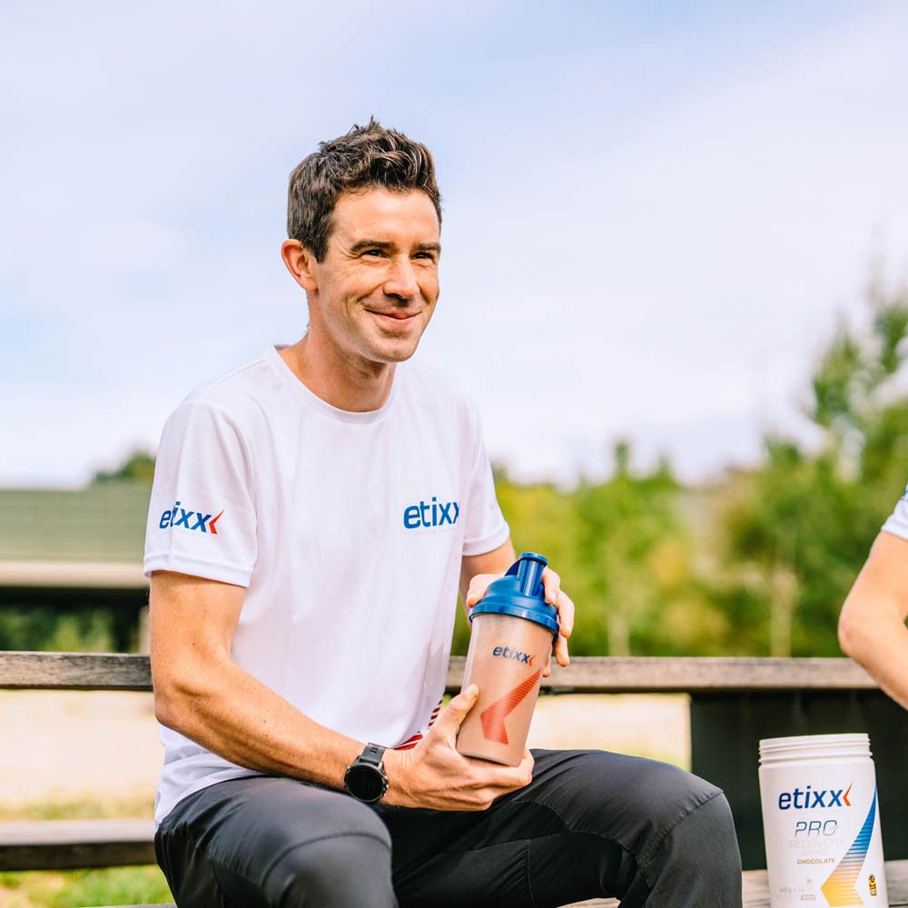 Homme tenant un shaker. Le logo "etixx" est visible sur le shaker et le t-shirt.