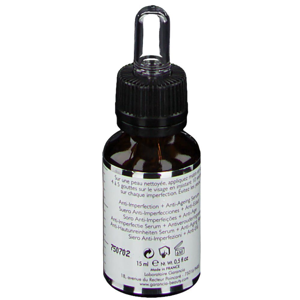 Bruine glazen fles met zwarte dop en pipet. Tekst op de achterkant. Opschrift: L'Elixir du Marabout. Merk: Garancia.