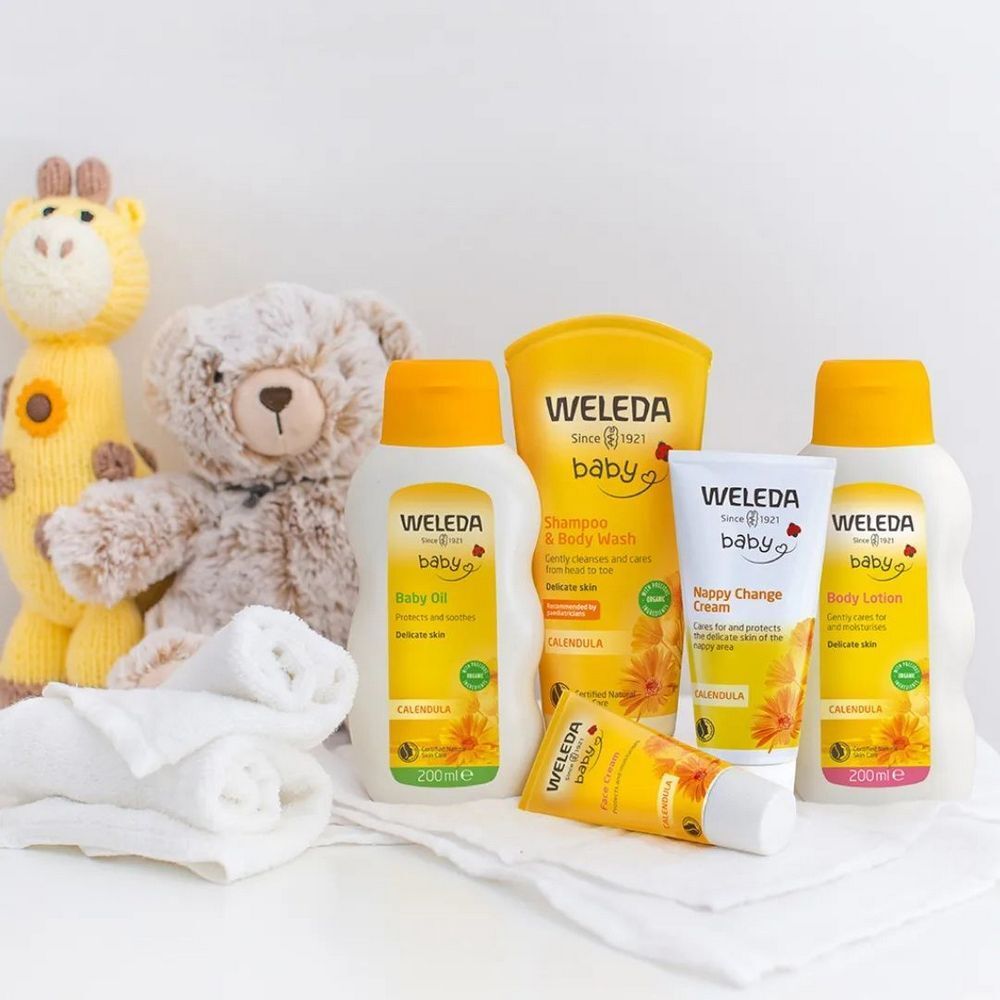 Weleda Baby Produkte: Baby Öl, Shampoo, Creme, Lotion. Gelbe Verpackungen, Text: Baby. Kuscheltiere und Handtücher.