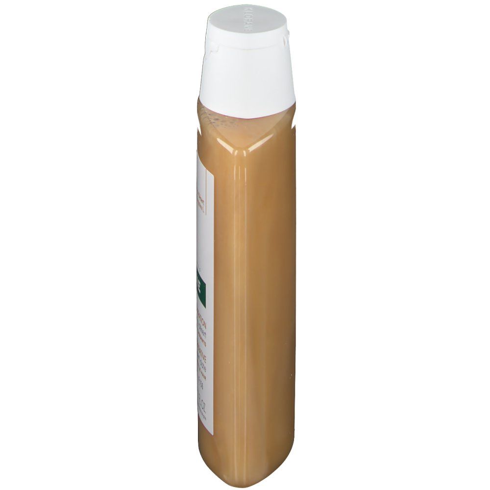 Flacon de shampooing étroit et allongé avec bouchon blanc. Étiquette avec informations produit. Liquide doré visible.