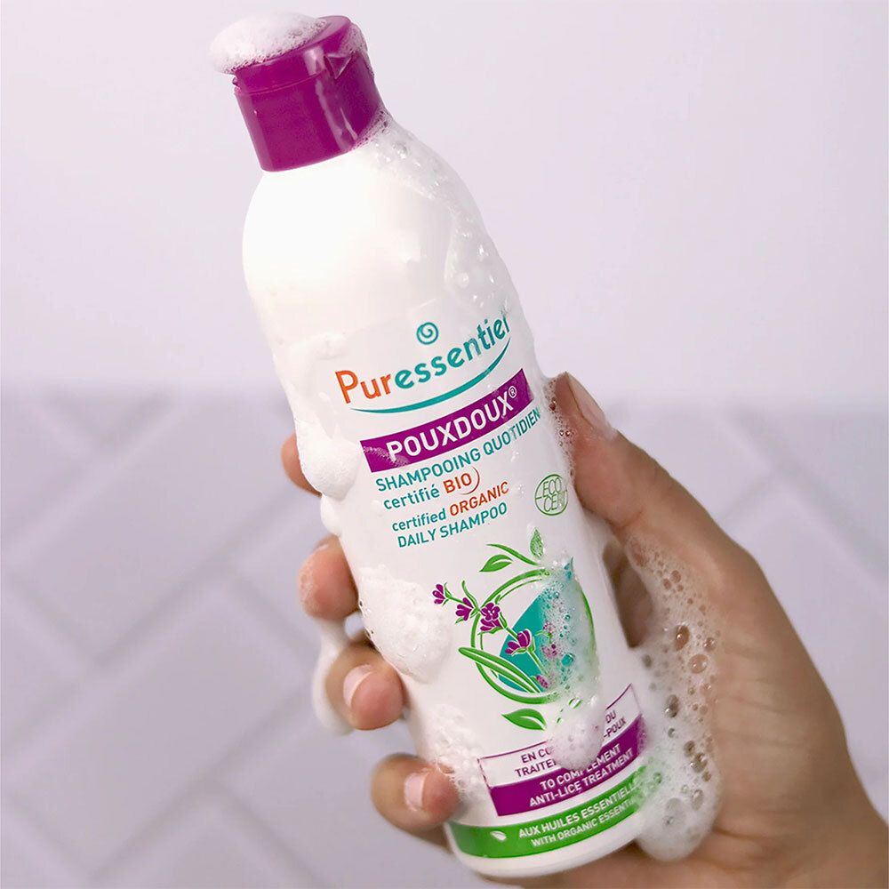 Fles met paarse dop, bedekt met schuim. Opschrift: Puressentiel Poudoux® Shampooing.
