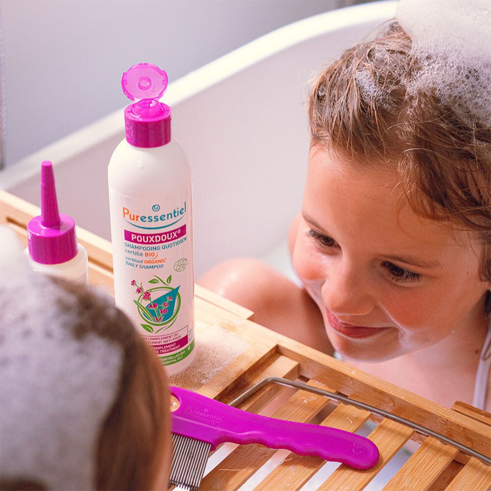 Kind in bad met shampoo fles en luizenkam. Opschrift: Puressentiel Poudoux®.
