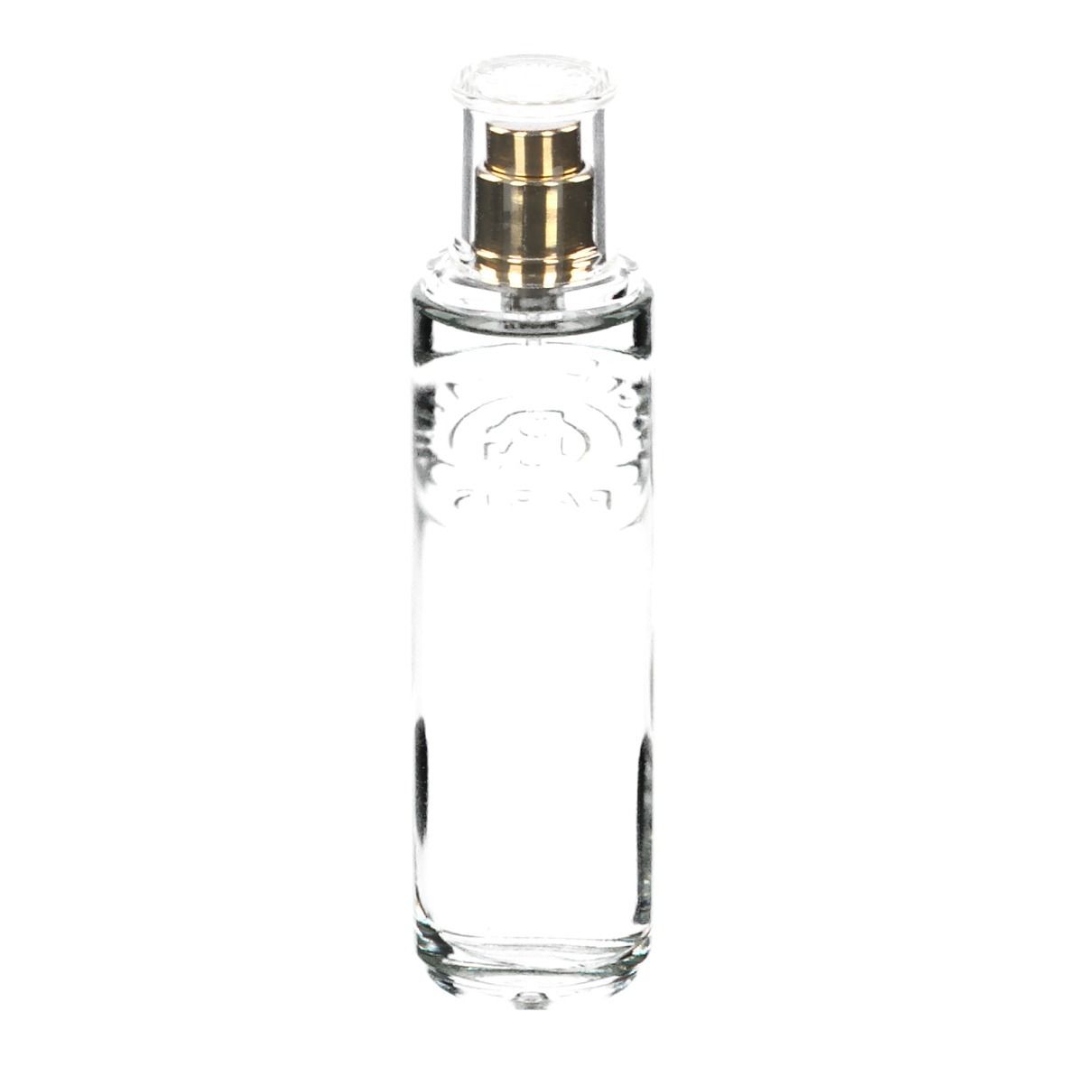 Transparante glazen fles met gouden verstuiver. Bevat heldere vloeistof. Cilindrische vorm.