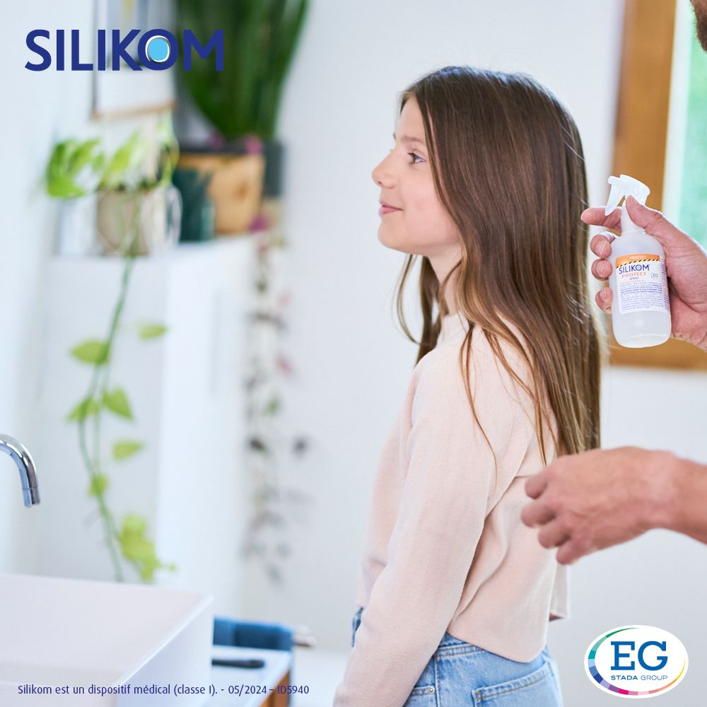 Fille se faisant vaporiser les cheveux. Flacon de produit visible. Arrière-plan: salle de bain.