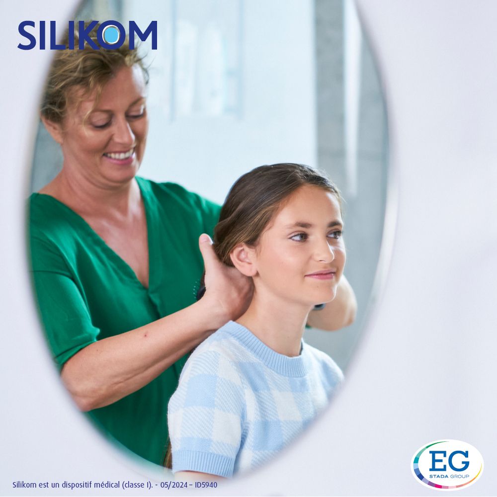 Mère peignant les cheveux de sa fille. Miroir en arrière-plan. Produit non visible.