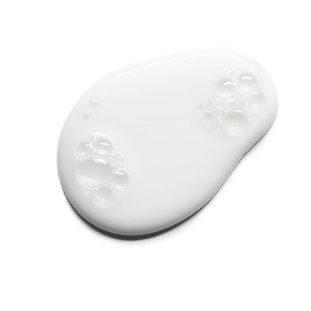Goutte de BIODERMA Atoderm Crème de douche. Texture crémeuse blanche avec bulles. Sur fond blanc.