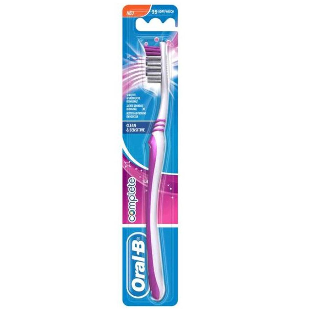 Brosse à dents dans son emballage. Manche blanc avec accents roses. Tête avec brins roses et blancs. Marque Oral-B.
