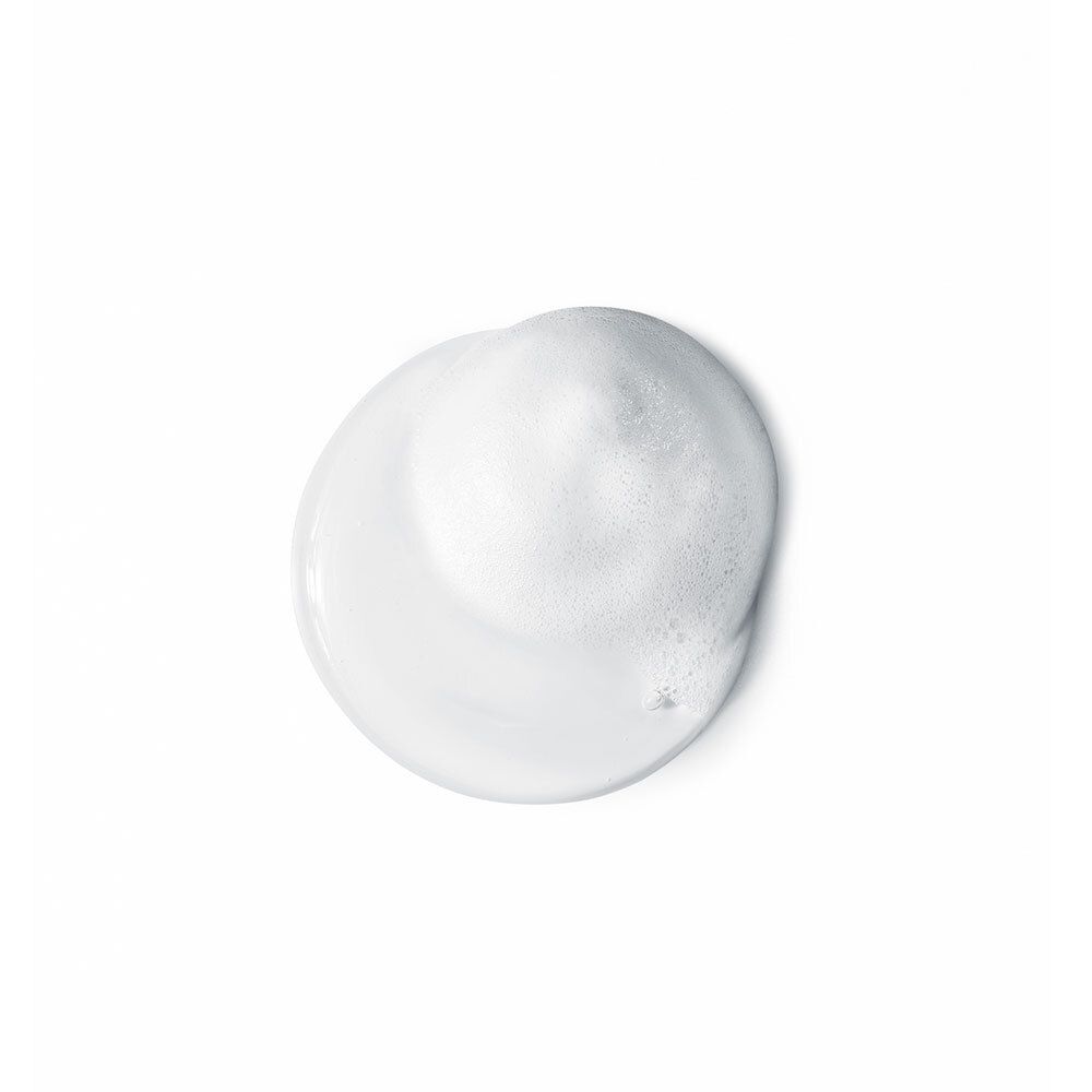 Gros plan sur de la mousse nettoyante blanche sur fond blanc.