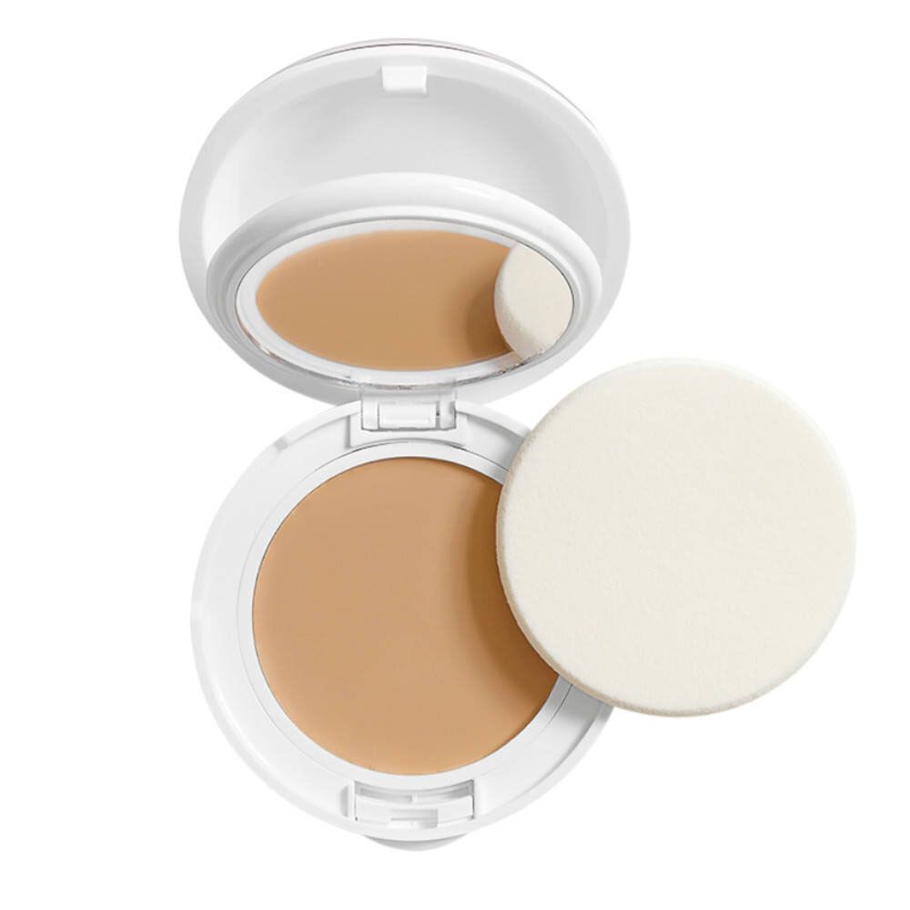 Maquillage compact ouvert. Boîtier blanc avec miroir et éponge. Crème beige clair. Éponge à côté.