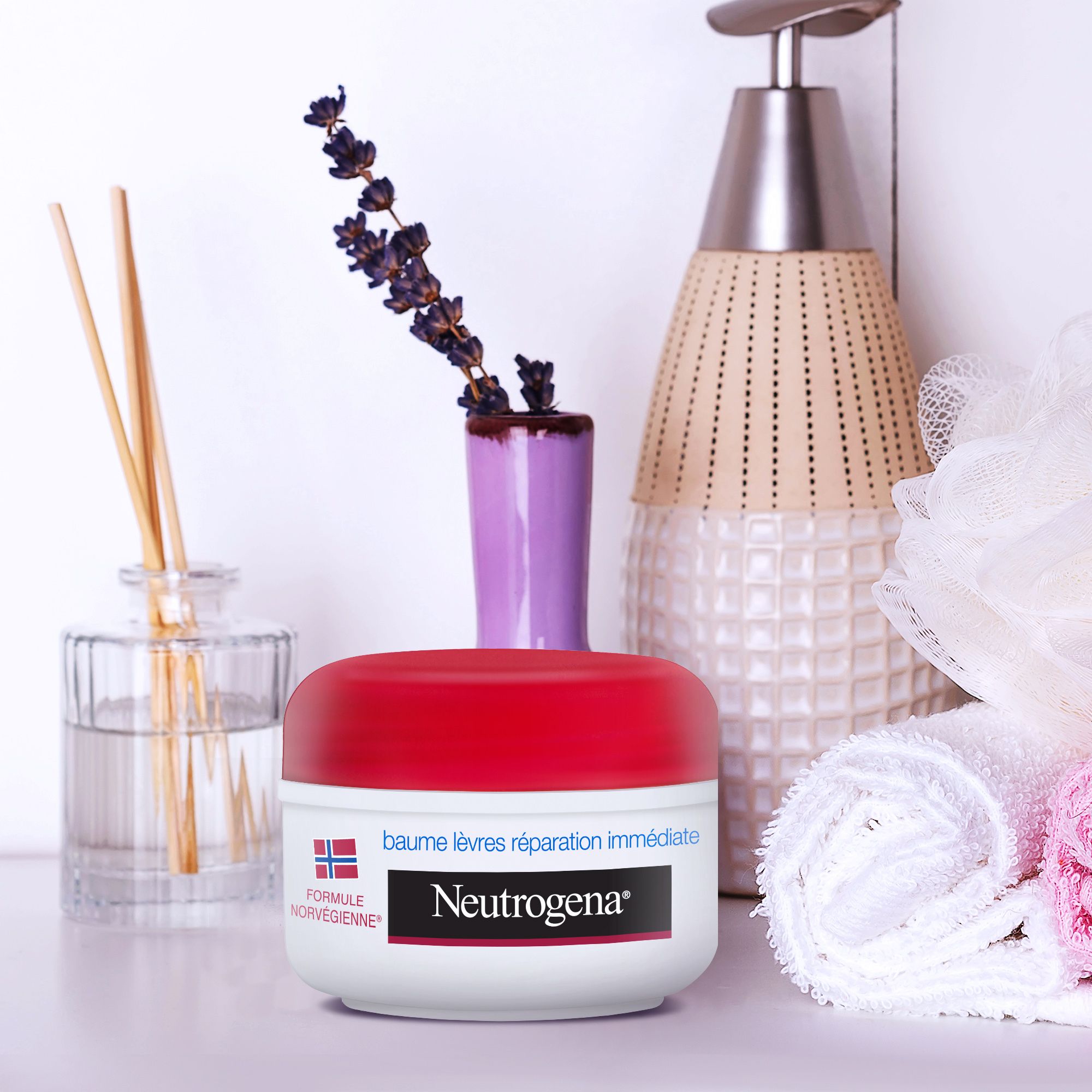 Baume lèvres et narines Neutrogena avec accessoires. Pot blanc, couvercle rouge. Sur une table.