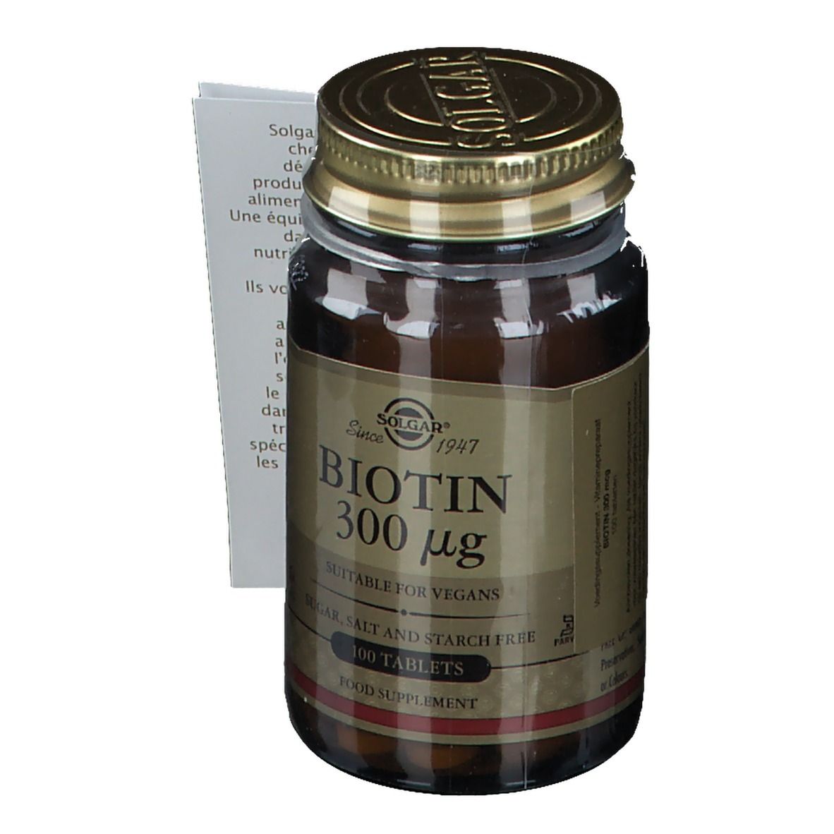 Flacon en verre brun avec couvercle doré. Étiquette "Biotin 300 µg". Notice avec texte. "Suitable for vegans".
