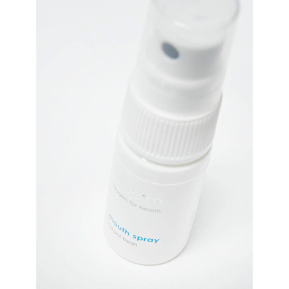 Gros plan du spray buccal blanc avec tête de pulvérisation. Inscription : bluem, mouth spray, instant fresh.