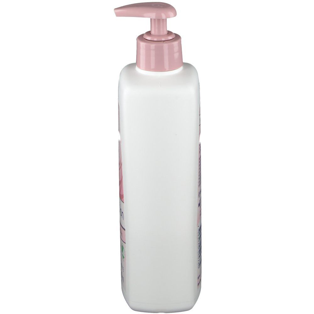 Flacon blanc avec pompe rose. Vue latérale. Inscriptions sur le flacon. Produit pour le soin de la peau.