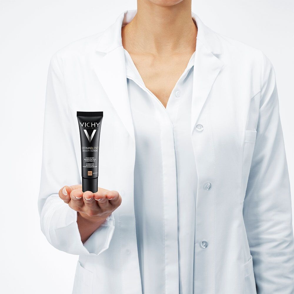 Personne tenant un tube de Vichy Dermablend 3D Correction Nr. 55 Bronze. La personne porte une blouse blanche.