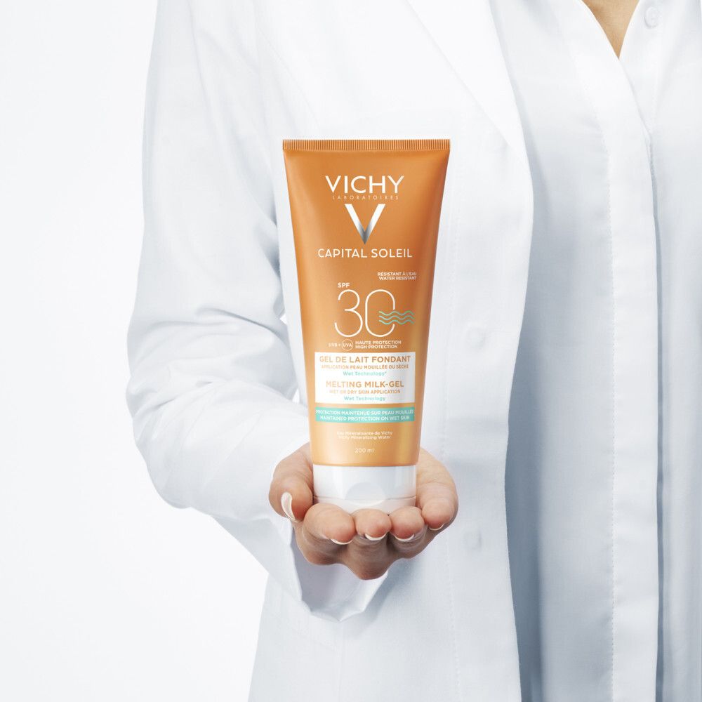 Personne en blouse blanche tenant un tube. Inscriptions: VICHY, CAPITAL SOLEIL, SPF 30. Texte: Gel de Lait Fondant, Melting Milk-Gel.